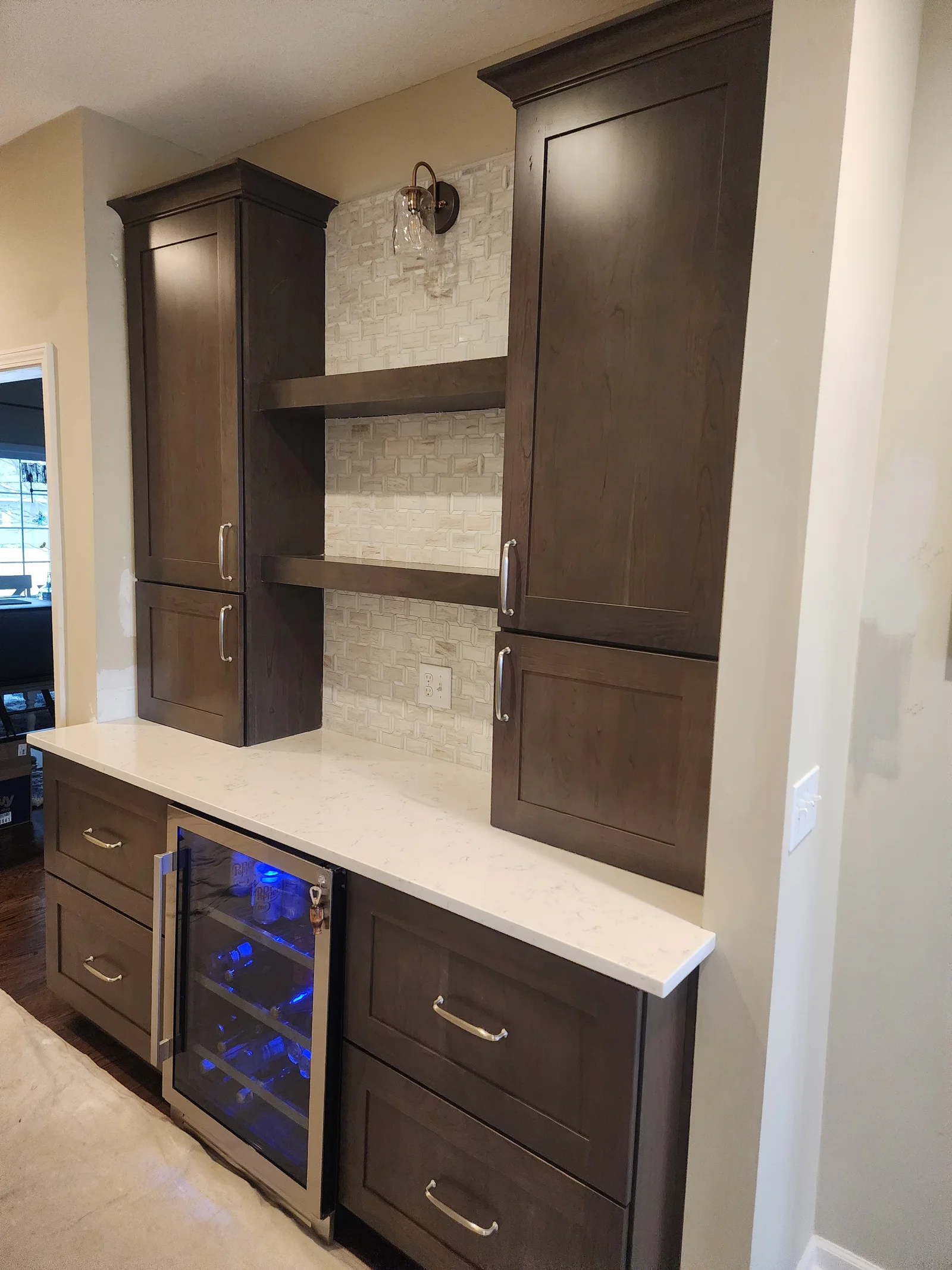 Dark stained shaker cabinets with quartz countertop, beverage cooler, and mosaic tile backsplash in built-in bar